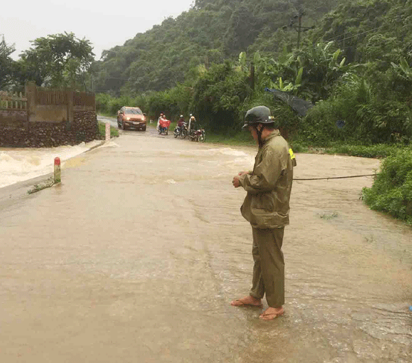Công an xã San Thàng (thành phố Lai Châu) đứng chặn không cho người dân tham gia thông qua cầu ngập tràn đường San Thàng - Thèn Sin khi nước lũ. (Ảnh chụp ngày 11/7).