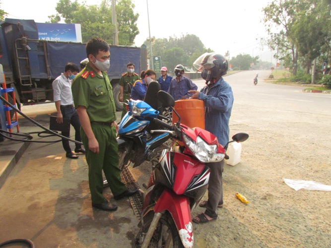 Thành viên Ban Chỉ đạo phòng, chống dịch Covid - 19 thị trấn Phong Thổ cùng lực lượng Công an huyện Phong Thổ tuyên truyền người dân không mua xăng tích trữ trong nhà. (Ảnh chụp 15 giờ 45 chiều ngày 31/3 tại cửa hàng xăng trên địa bàn thị trấn Phong Thổ).
