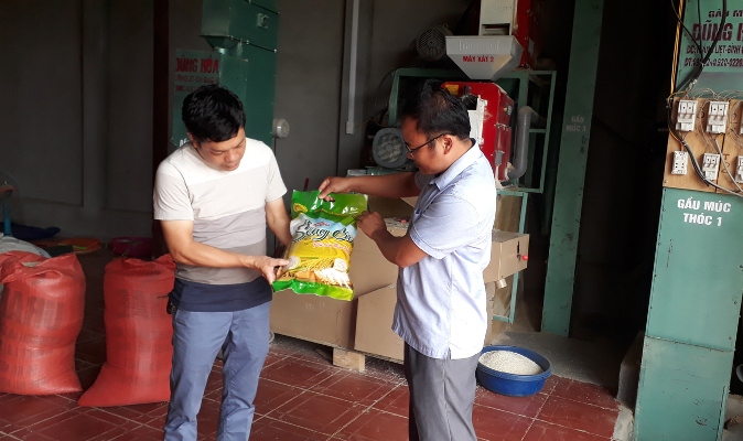 Ông Nguyễn Văn Yên (bên trái) - Giám đốc HTX xây dựng Thanh Xuân (huyện Than Uyên) giới thiệu mẫu mã bao bì sản phẩm gạo séng cù chất lượng cao của huyện. 