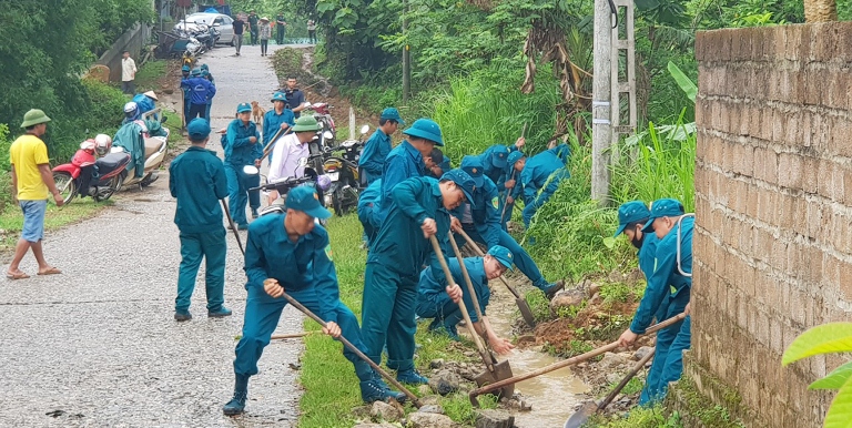 Lực lượng tự vệ cùng người dân khơi thông cống rãnh, vệ sinh khu dân cư (thị trấn Tân Uyên). 