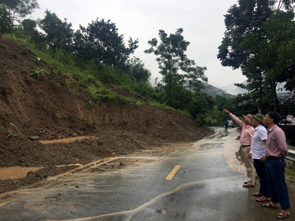 Cán bộ xã Mường Kim theo dõi khối lượng đất đá đang sạt trượt xuống tiềm ẩn nguy hiểm khu vực Nà Phạ, bản Mường 1.