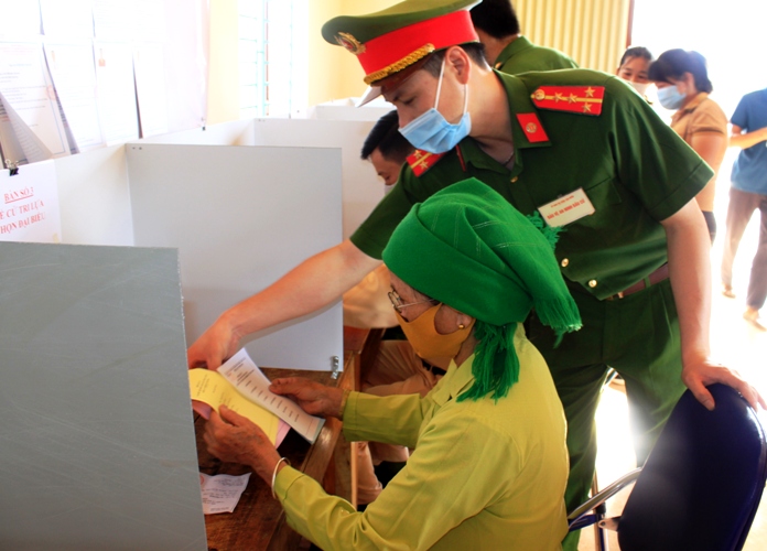 Cán bộ chiến sỹ Công an huyện Tân Uyên hướng dẫn người dân cách thức viết phiếu bầu. 