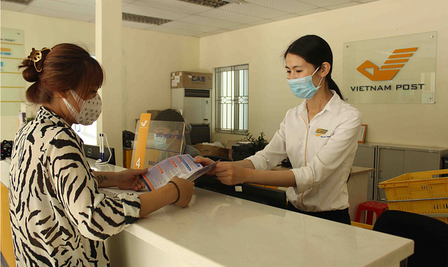 Giao dịch viên đại lý thu Bưu điện thành phố Lai Châu tuyên truyền cho lao động tự do tham gia bảo hiểm xã hội tự nguyện.