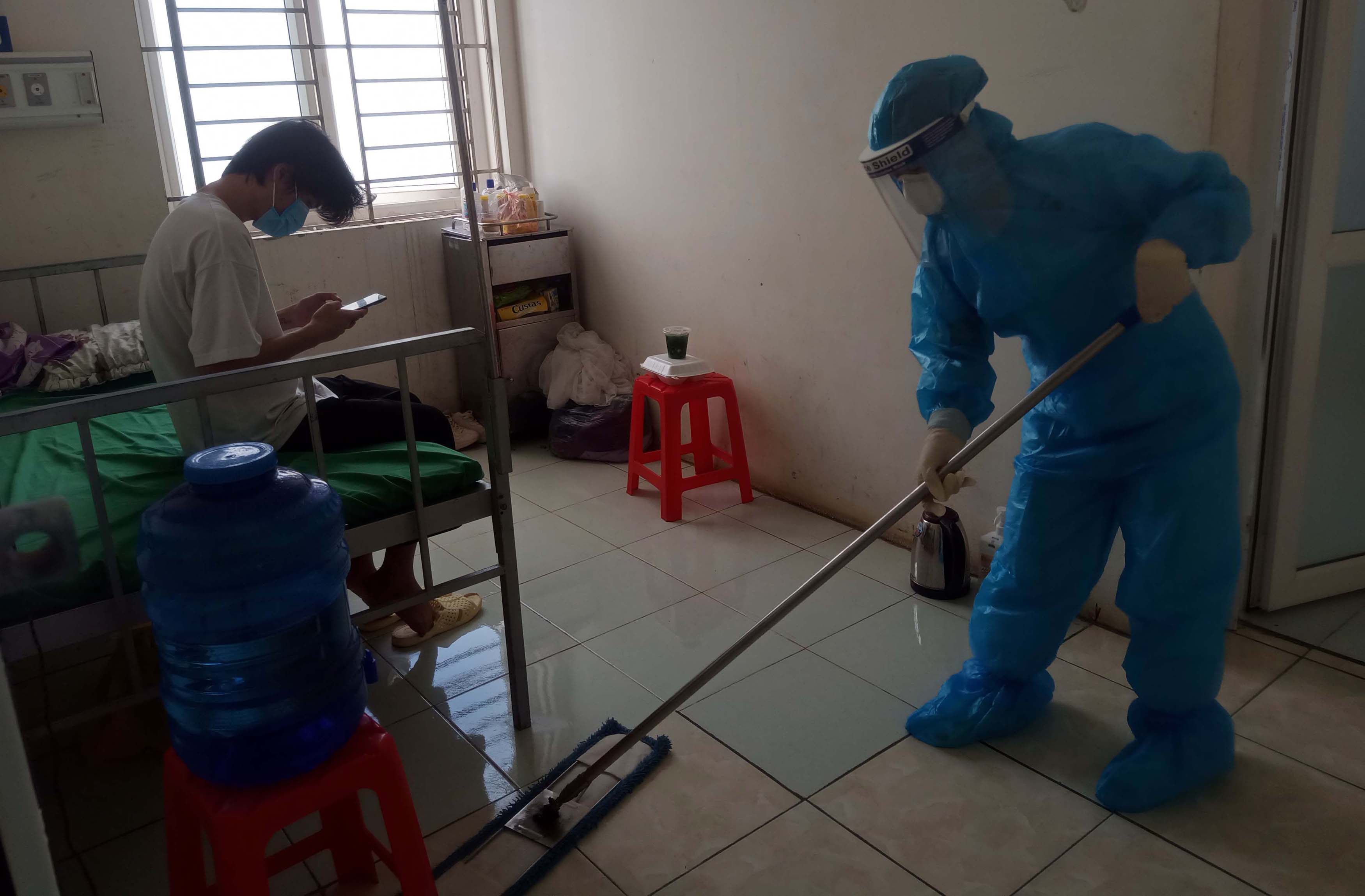 Hộ lý Đoàn Thị Liên thực hiện lau chùi bằng hóa chất để hạn chế môi trường trú ngụ của virút trong phòng điều trị bệnh nhân nhiễm Covid - 19.