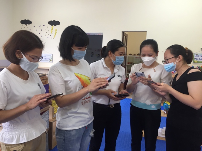Giáo viên trường Mầm non Đoàn Kết (thành phố Lai Châu) hướng dẫn nhau cùng cài đặt ứng dụng sổ sức khỏe điện tử qua điện thoại thông minh. 