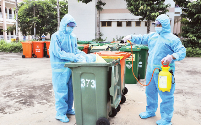 Công nhân Công ty Môi trường đô thị tiến hành khử khuẩn rác thải y tế liên quan dịch Covid-19. Ảnh: nhandan.vn