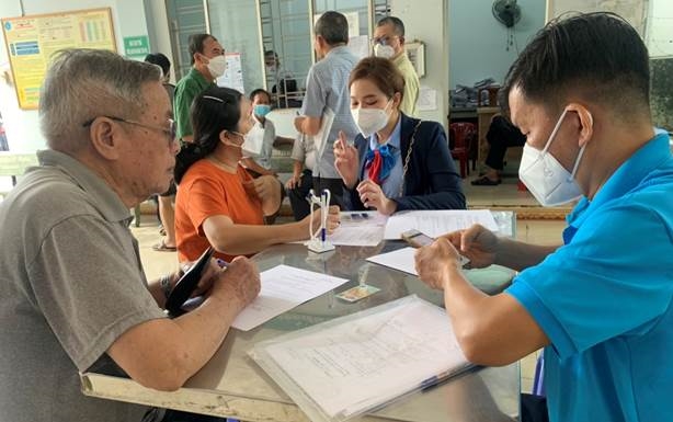 Cán bộ BHXH tỉnh Đồng Nai và nhân viên ngân hàng hướng dẫn người dân làm thủ tục nhận lương hưu qua tài khoàn cá nhân 