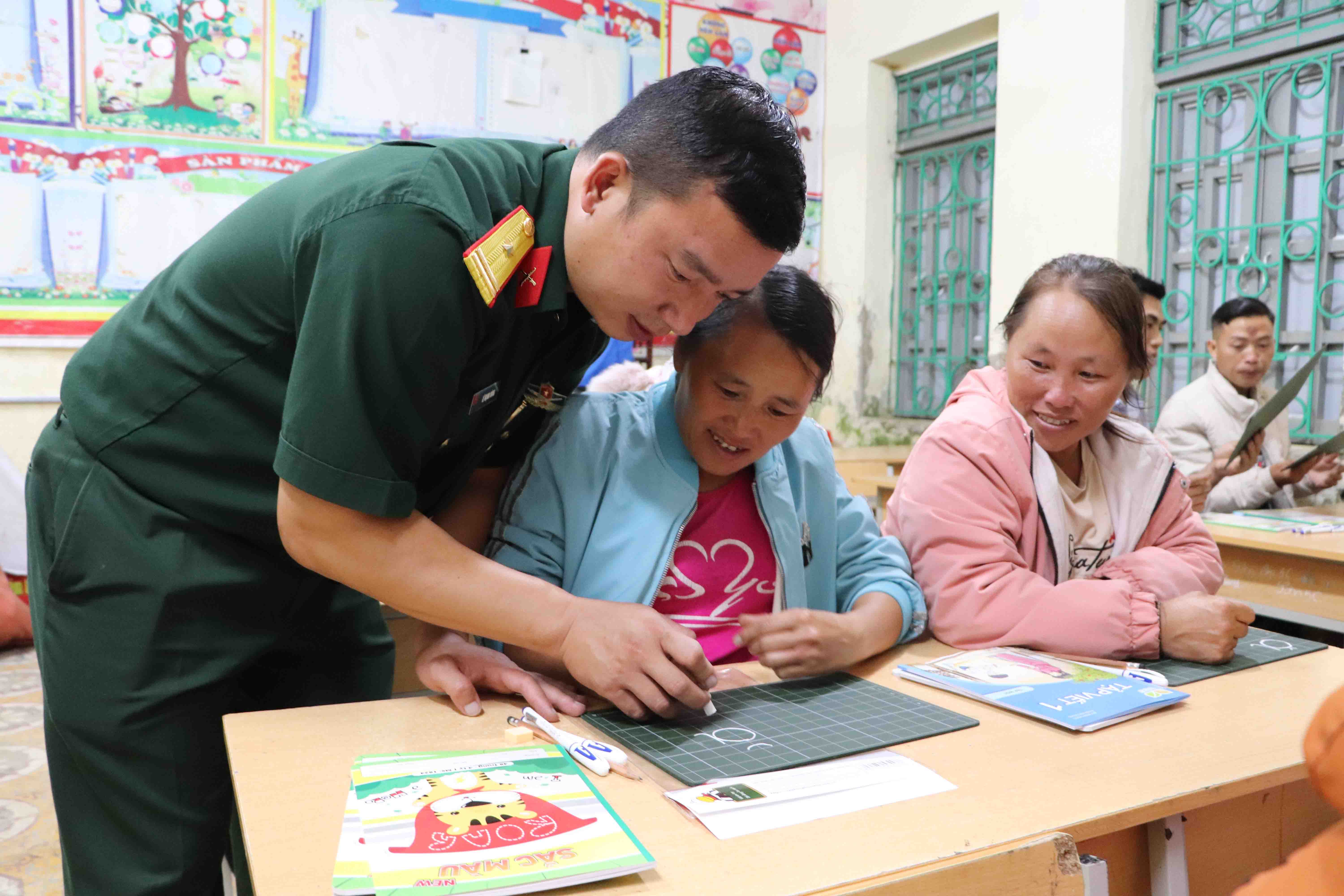 Cán bộ Đội SX&XDCSCT số 3 dạy chữ cho người dân xã Dào San.