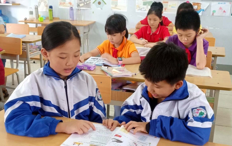 Em Duyên (bên trái) hướng dẫn bạn học trên lớp.