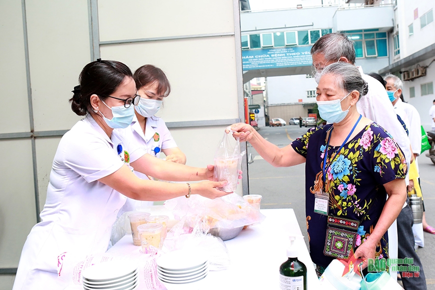 Bệnh nhân phấn khởi đón nhận những cốc cháo miễn phí từ tay cán bộ, nhân viên Khoa Dinh dưỡng. Ảnh: HẢI THANH 